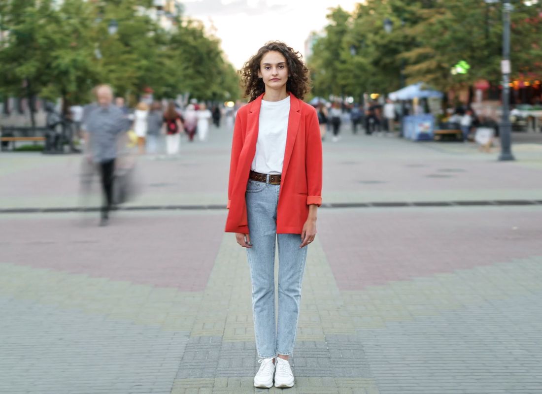 devojka u crvenom sakou beloj majici i farmerkama pozira