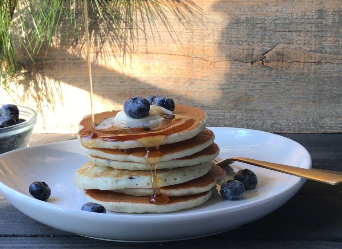 američke palačinke na tanjiru sa javorovim sirupom i borovnicama